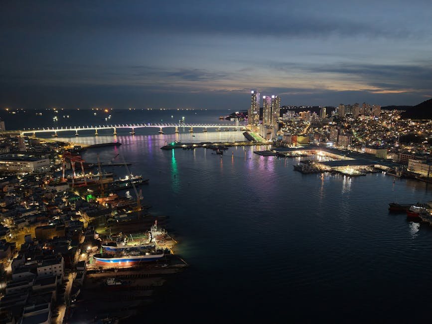 Stunning aerial view of Busan's Gwangan Bridge at night with cityscape lights reflecting on the water.