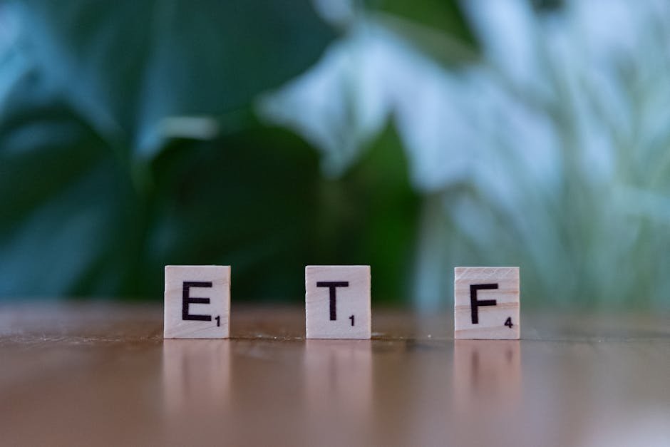 Scrabble tiles spelling ETF on a wooden surface with blurred green background.