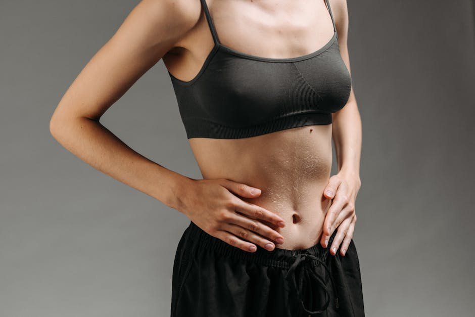 Close-up of a woman's torso in a studio setting, emphasizing skin texture and athletic form.